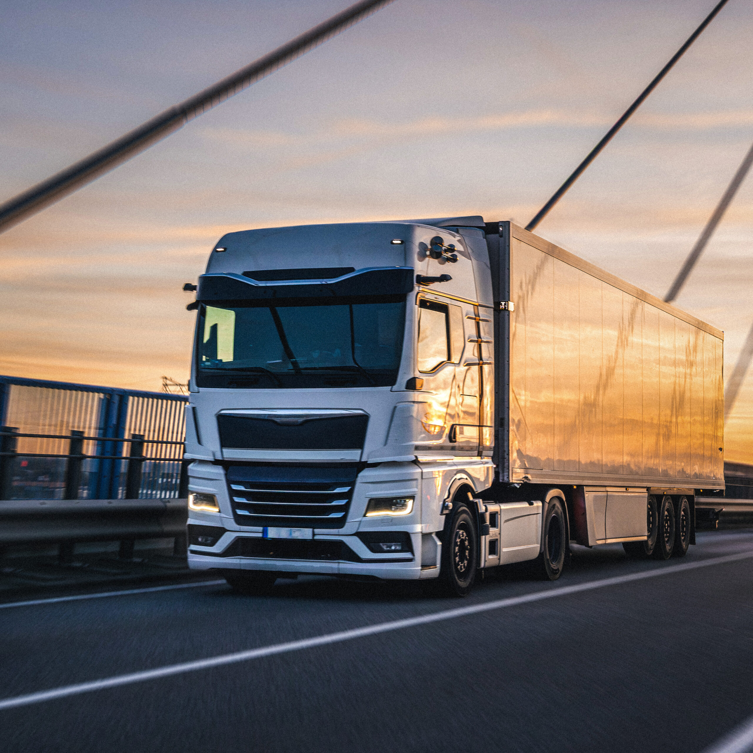 White truck crossing bridge at sunset. Urban logistics in motion.